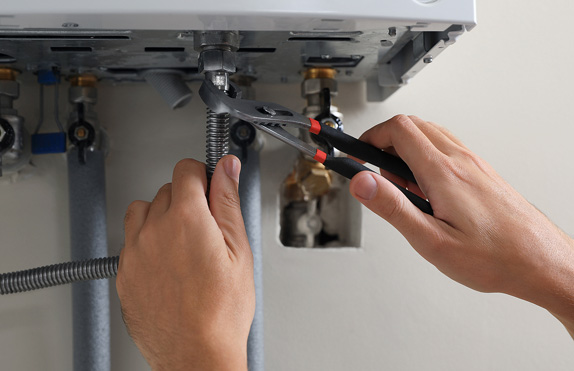 picture of a plumber with a wrench fixing a boiler