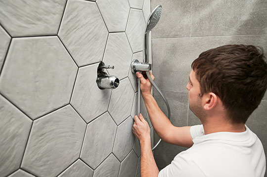 man with brown hair installing a shower